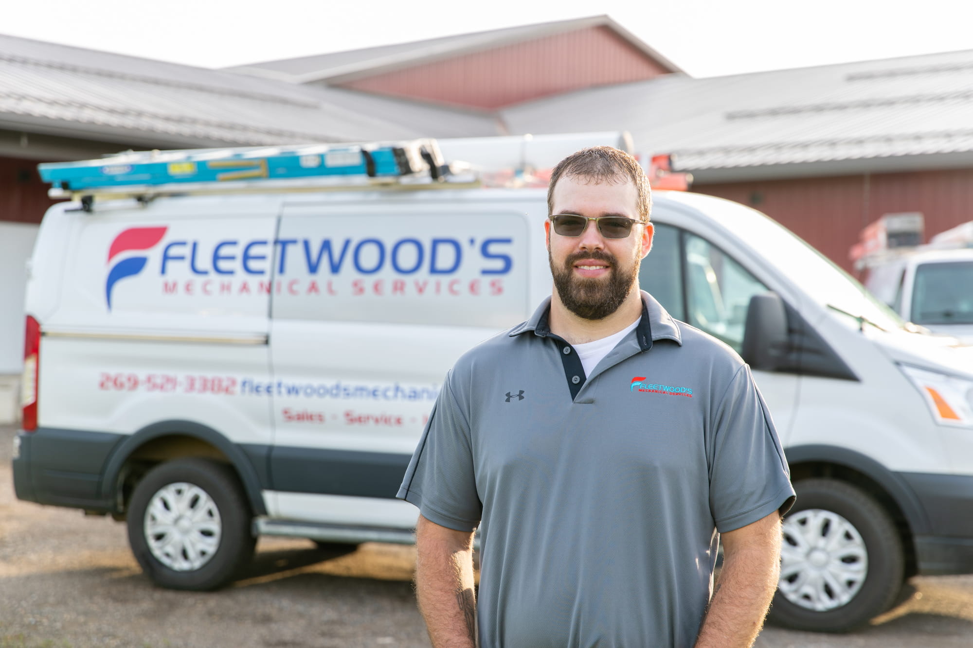 An HVAC technician standing in front of a Fleetwood's Heating & Cooling truck.